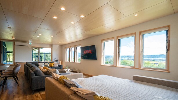 Une pièce spacieuse avec un grand lit, un canapé et un téléviseur fixé au mur.