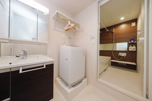 A bathroom with a white sink, mirror, and a shower area with wooden walls. - Pacific Coast Enoshima by Tranova (Fujisawa)