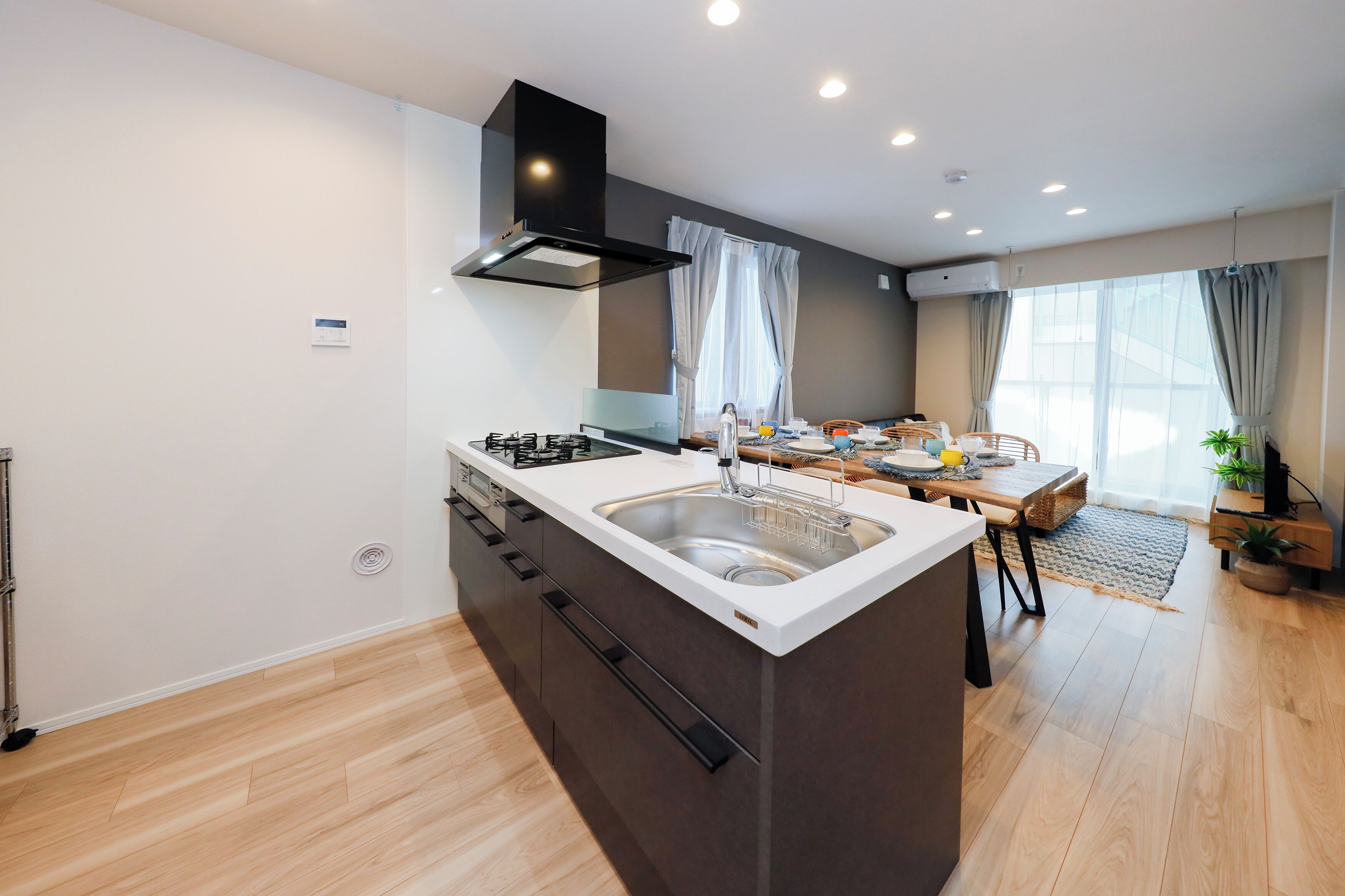Una cocina moderna con una isla central, un comedor con mesa y sillas, y un amplio ventanal con cortinas.
