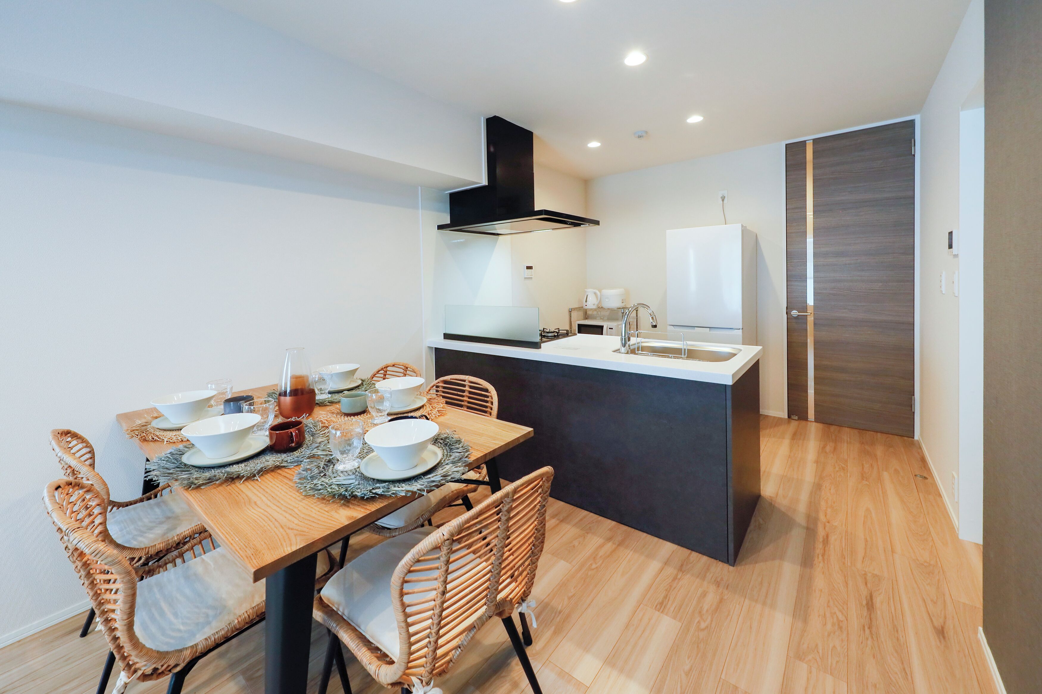 Una cocina moderna con comedor, suelo de madera e isla integrada con pileta.