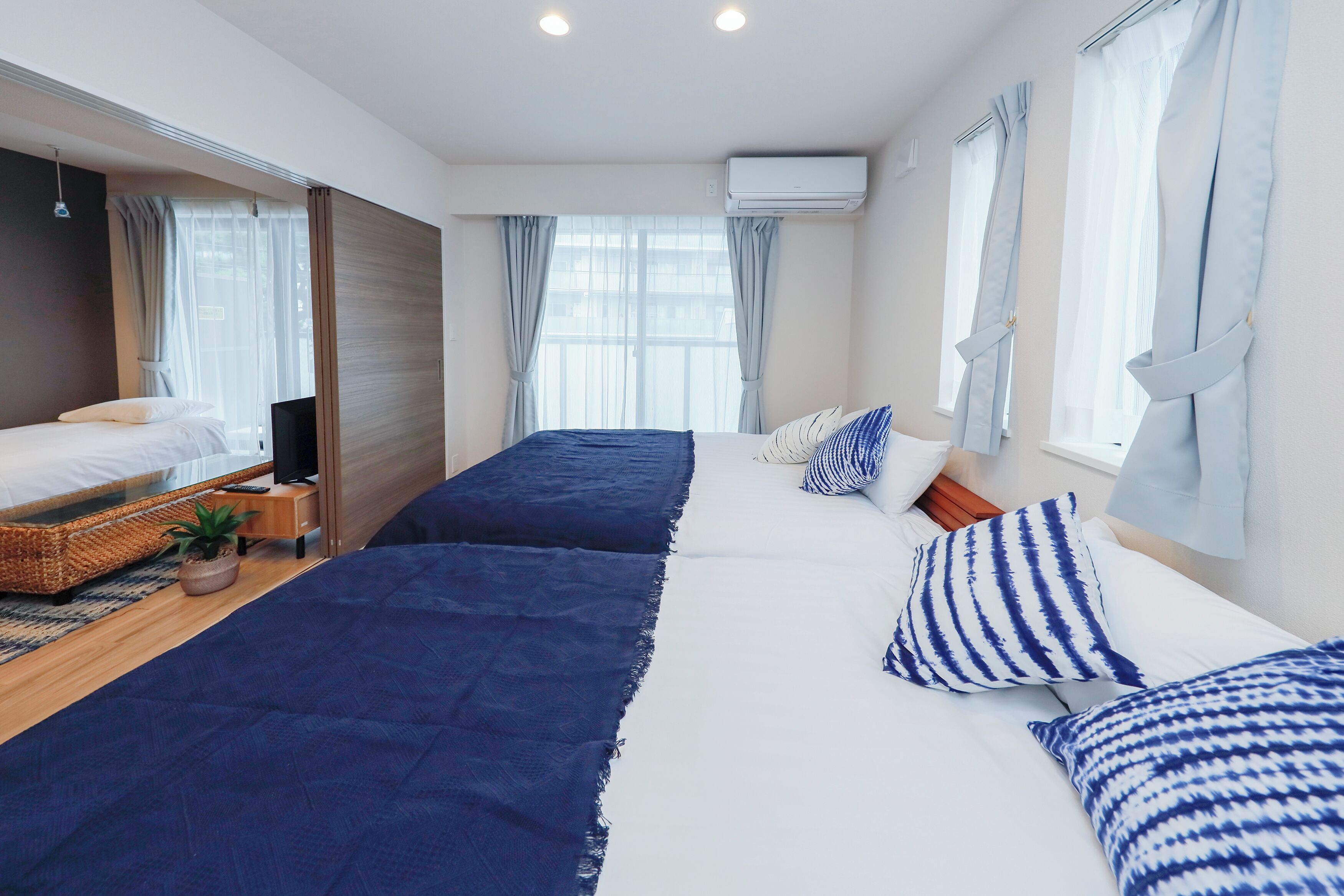 Ein Hotelzimmer mit zwei Betten, einem Fernseher, einem kleinen Tisch und einem Fenster mit Vorhängen.
