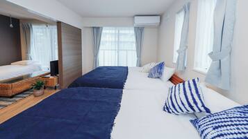 Ein Hotelzimmer mit zwei Betten, einem Fernseher, einem kleinen Tisch und einem Fenster mit Vorhängen.