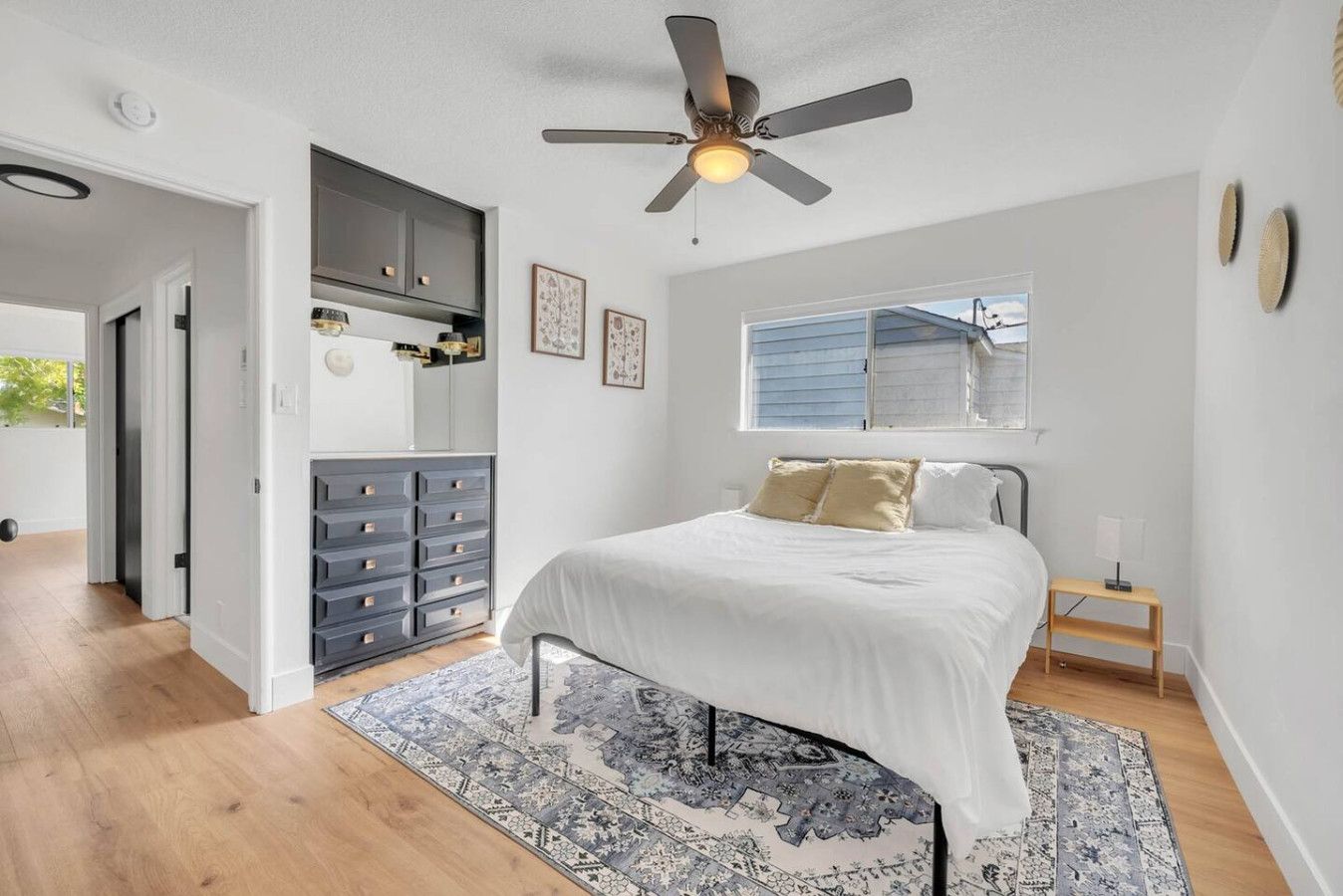A bedroom with a bed, a ceiling fan, a dresser, and a window.