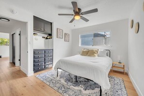 A bedroom with a bed, a ceiling fan, a dresser, and a window. - Main Street Retreat in Roseville (Roseville)