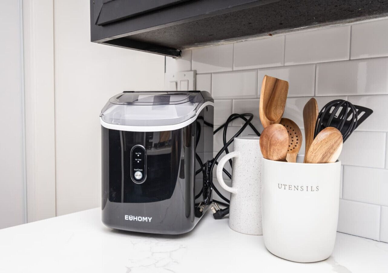A kitchen with a modern appliance, a mug labeled 'UTENSILS,' and wooden utensils.