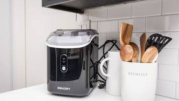 A kitchen with a modern appliance, a mug labeled 'UTENSILS,' and wooden utensils.