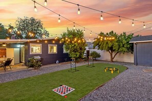 A backyard with a chessboard, a barbecue grill, and a dining area under string lights. - Main Street Retreat in Roseville (Roseville)