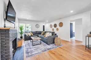 A modern living room with a stone fireplace, grey sofa, wooden coffee table, and decorative wall art. - Main Street Retreat in Roseville (Roseville)