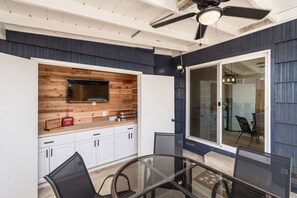 A modern kitchen with a wooden backsplash, white cabinets, and a glass dining table. - Main Street Retreat in Roseville (Roseville)