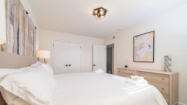 Een hotelkamer met een groot bed, een bedlampje, een dressoir en een schilderij aan de muur.