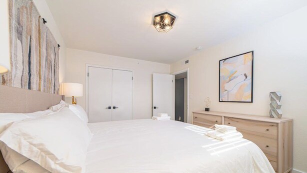Ein Hotelzimmer mit einem großen Bett, einer Nachttischlampe, einem Schminktisch und einem Bild an der Wand.