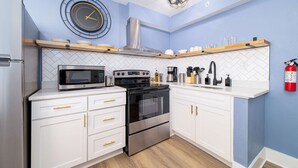 Eine moderne Küche mit weißen Schränken, einem Edelstahlbackofen, einer Mikrowelle und einer Uhr an der Wand.