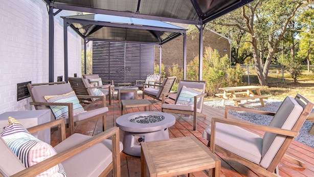 An outdoor patio with wooden furniture, a fire pit, and a covered area with a view of the surrounding landscape.