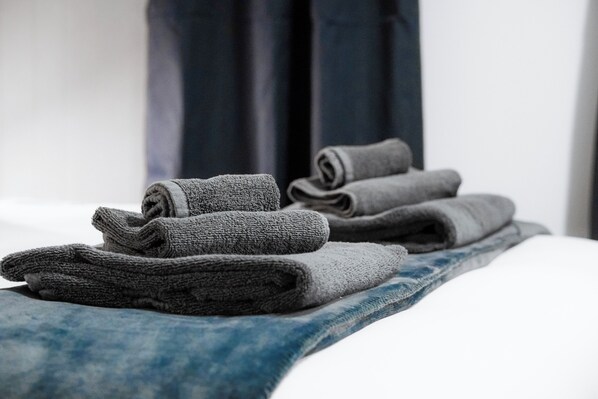 Ordentlich gefaltete Handtücher auf einem Bett mit blauem Kopfteil.