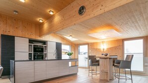 Una cocina moderna con paneles de madera, una isla central y un área de comedor con sillas y una mesa.