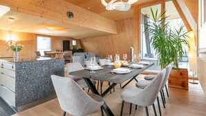 Un comedor moderno con techo de madera, una isla central con pileta y un ventanal que proporciona luz natural.