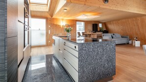 Una cocina moderna con encimera de granito, techo de madera y un comedor con sofá y mesa.