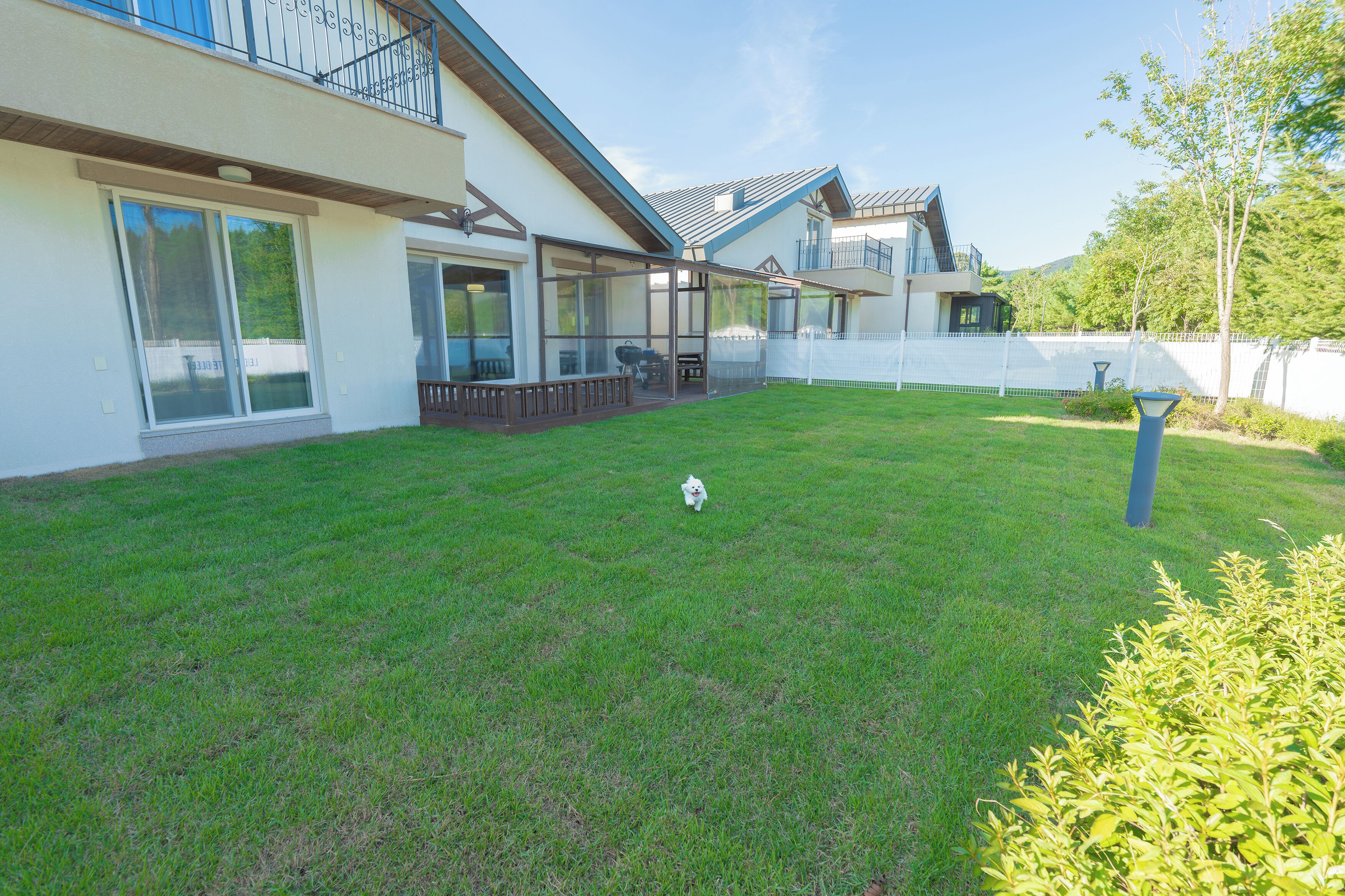 A modern house with a large glass window, a covered patio, and a well-maintained lawn.