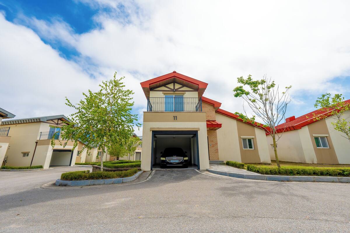 A modern building with a garage entrance, surrounded by well-maintained landscaping and a clear sky.