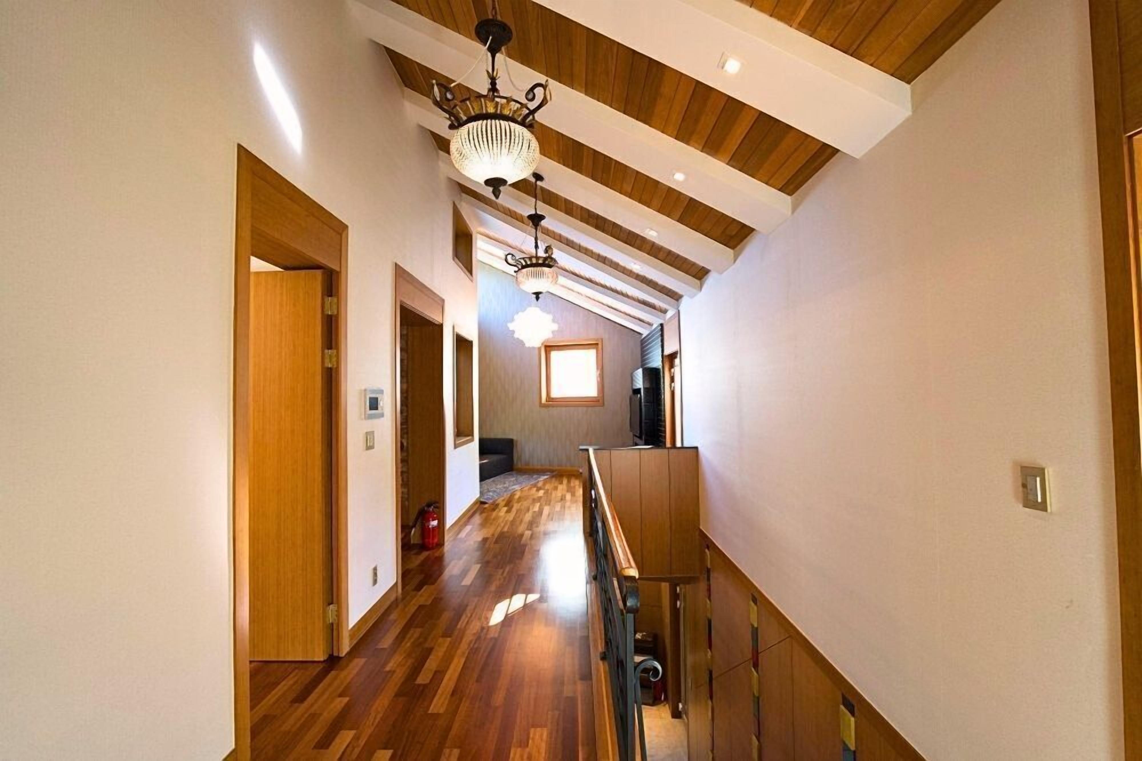 A hallway with wooden flooring and a sloped ceiling.