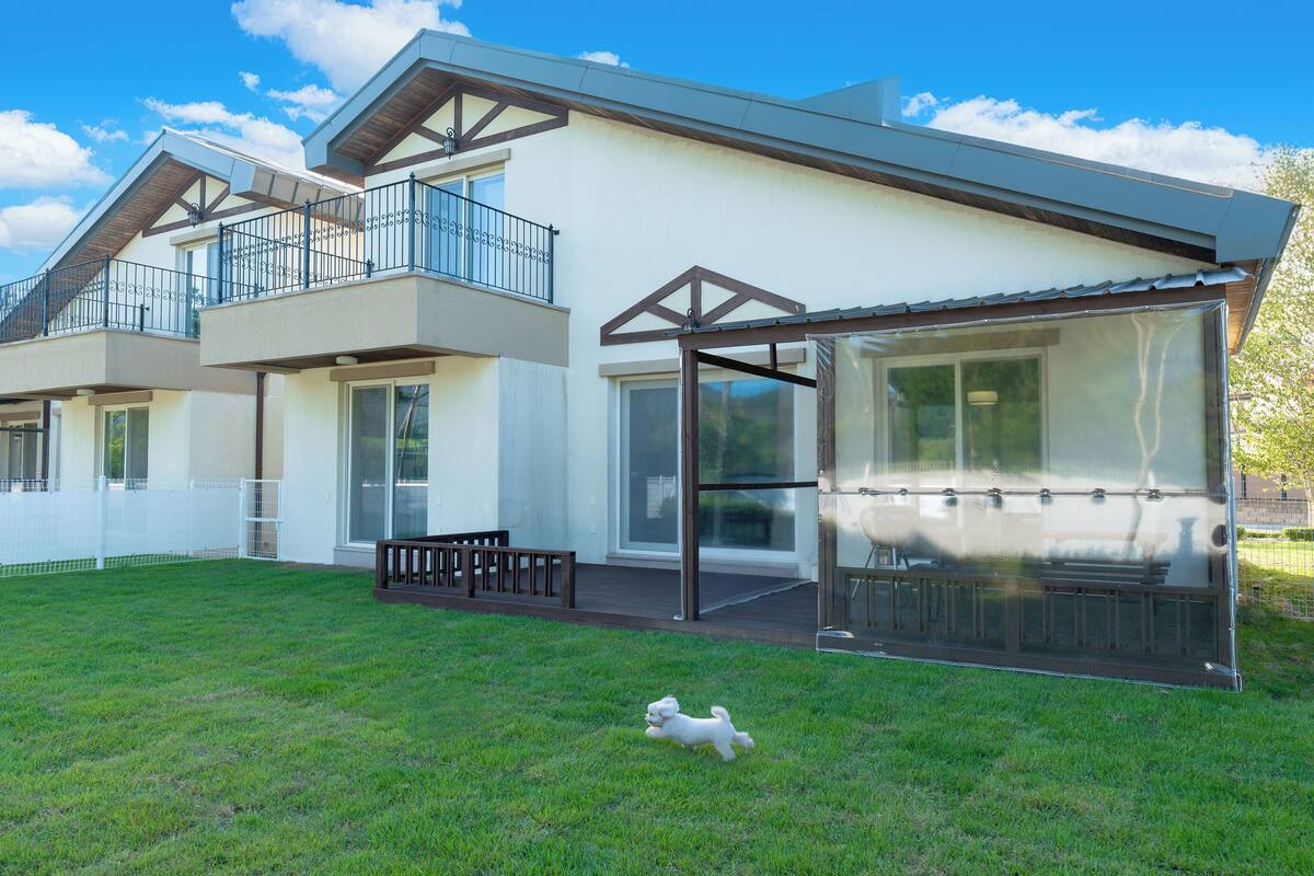 A modern two-story house with a covered patio and a fenced backyard.