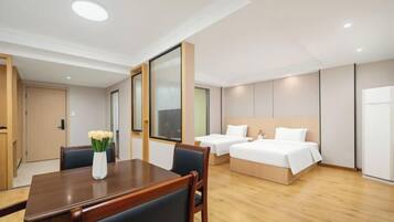 A hotel room with a wooden dining table, two beds, and a large window.