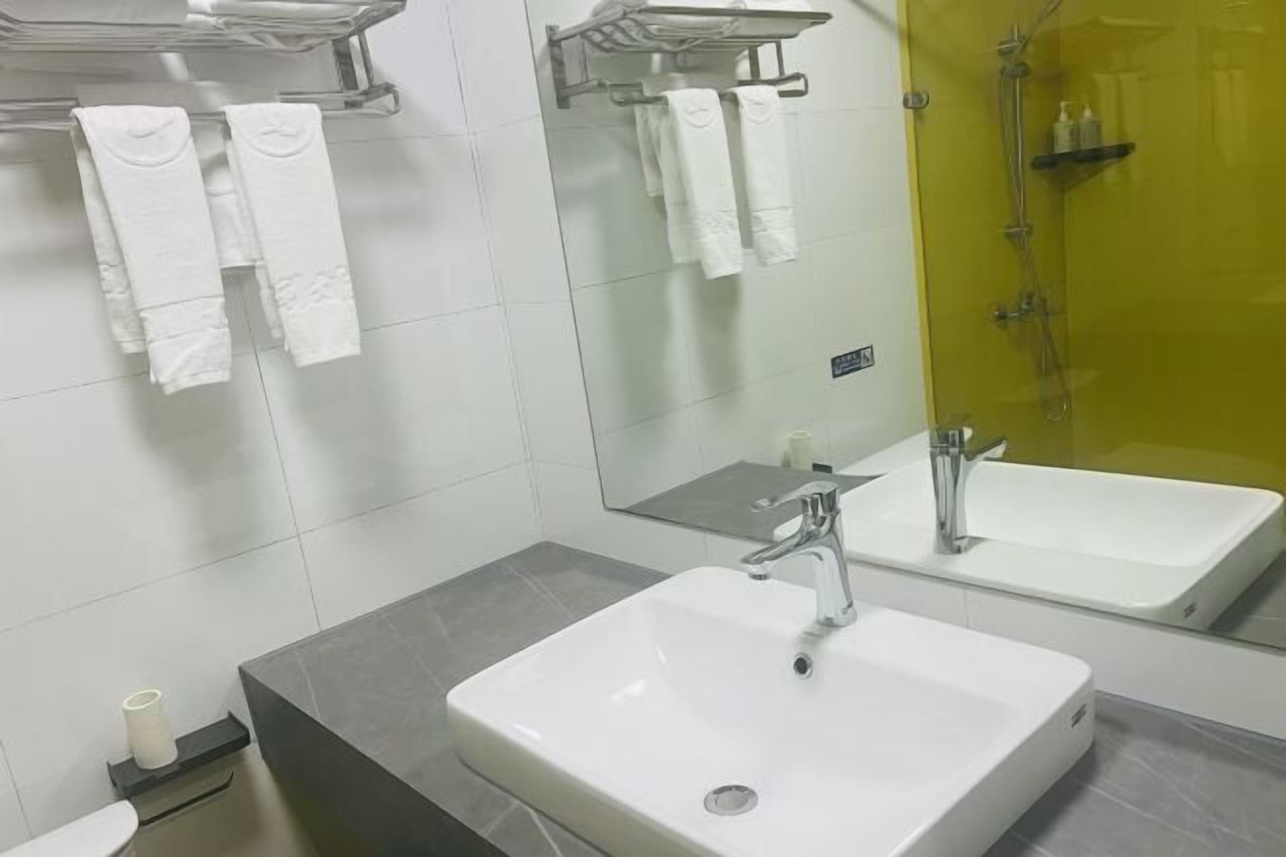 A bathroom with a white sink, a mirror, and a shower area.