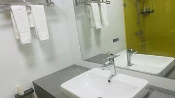 A bathroom with a white sink, a mirror, and a shower area.