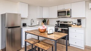 A modern kitchen with white cabinets, a stainless steel refrigerator, a microwave, and a coffee maker. - Studio on Main Street  (Roseville)