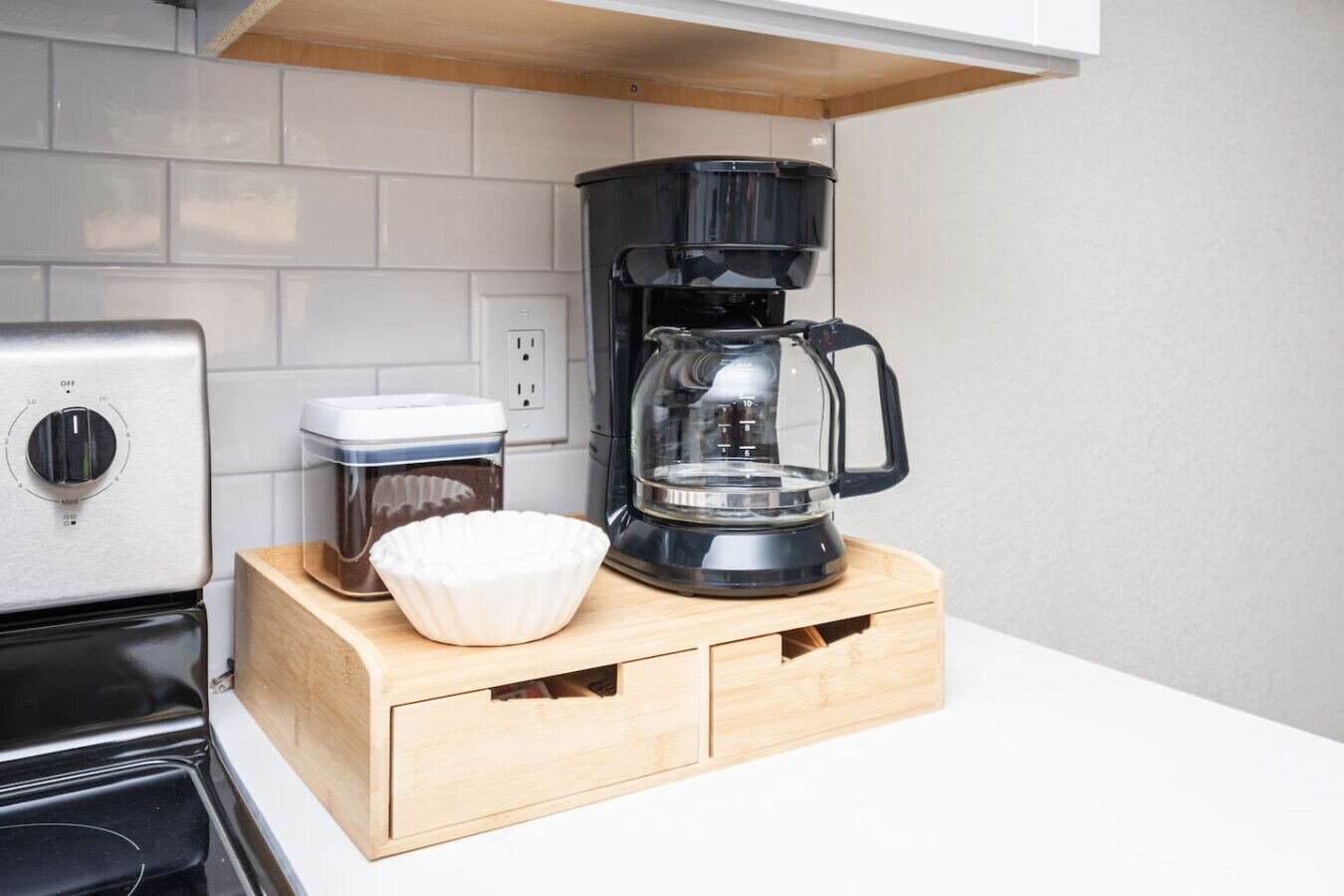 A kitchen with a coffee maker, a food processor, and a white bowl on a wooden countertop.