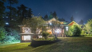 A two-story house with a visible garage and a well-lit front yard at night.