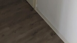 Una habitación con piso de madera, una puerta blanca con picaporte plateado y un objeto rojo en la pared.