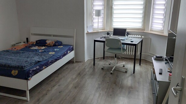 Un dormitorio con cama, escritorio y silla, y un radiador.