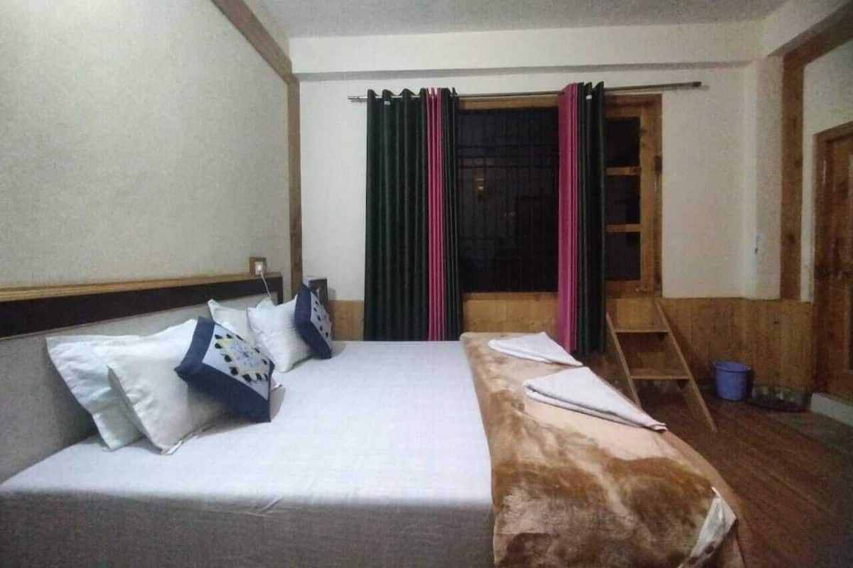 Ein Hotelzimmer mit Bett, Kissen, einer Holzleiter und einem Fenster mit Vorhängen.