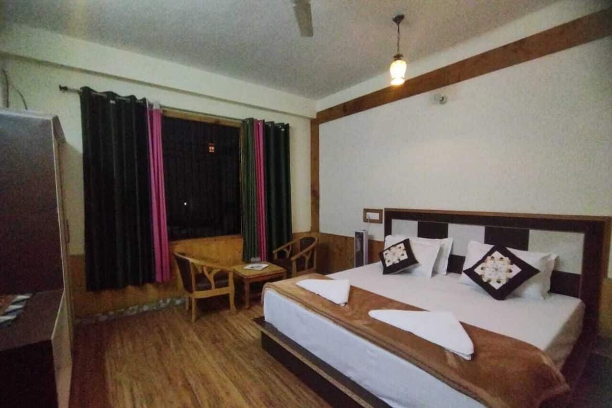 Ein Hotelzimmer mit Bett, Holzmöbeln, einem Schreibtisch und Vorhängen.