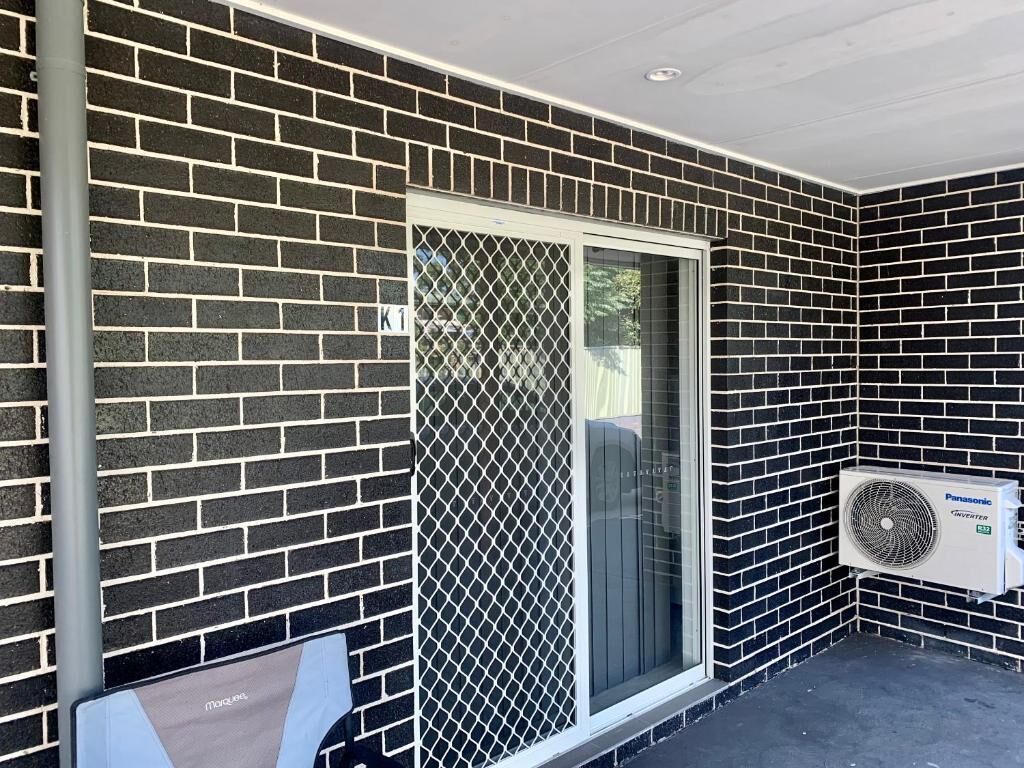 A brick exterior wall with a sliding glass door and a mounted air conditioning unit.