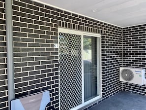 A brick exterior wall with a sliding glass door and a mounted air conditioning unit.