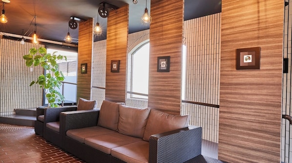 Eine moderne Lounge mit einer Couch, Korbstühlen und hängenden Pendelleuchten.