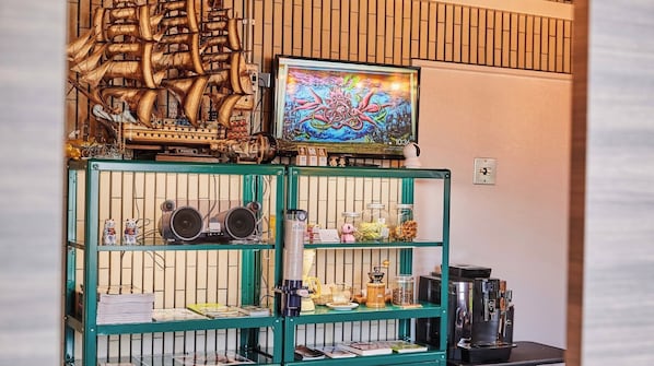 Eine Bar mit einem grünen Tresen, einem großen dekorativen Schiffsmodell, einem farbenfrohen Gemälde und einer Kaffeemaschine.