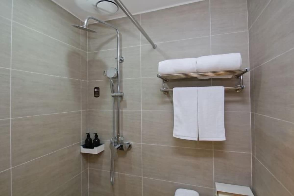 A modern bathroom with a shower, toilet, and towel rack.