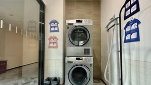 A laundry room with two stacked washing machines, a drying machine, and a wall-mounted ironing board. - HanTing Hotel (Xi'an Bianjiacun Subway Station) (Xi'an)