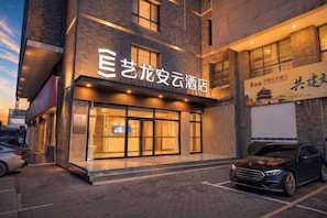 L’entrée d’un hôtel, avec une grande enseigne, un espace de stationnement et une voiture garée devant.