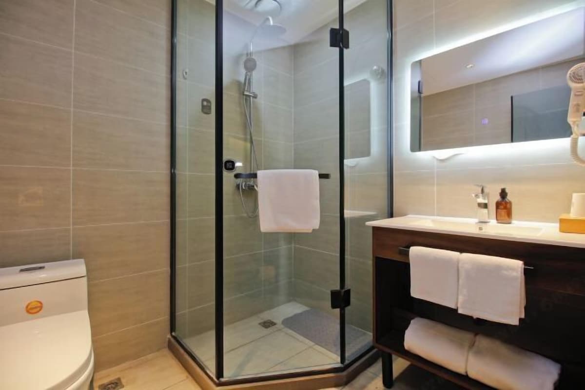 A modern bathroom with a glass-enclosed shower, a toilet, a sink with a mirror, and a towel rack.