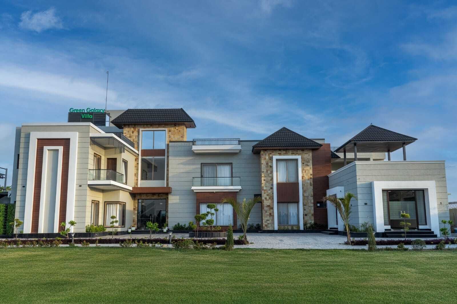 Een moderne, meerlaagse villa met een plat dak, grote ramen en een verzorgd gazon.