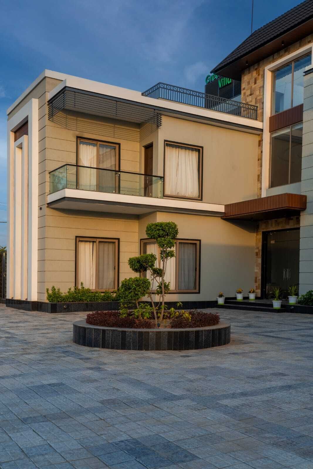 Un bâtiment moderne à deux étages, doté d’un balcon, de grandes fenêtres et d’une cour aménagée.