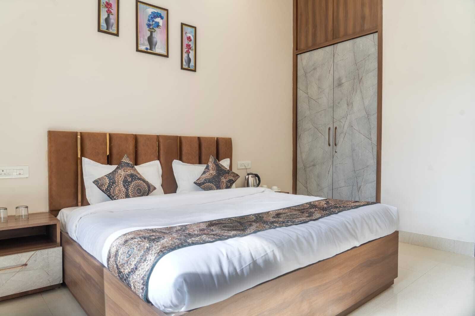 A neatly made bed with a patterned bedspread, a wooden headboard, and two bedside tables with glass containers.