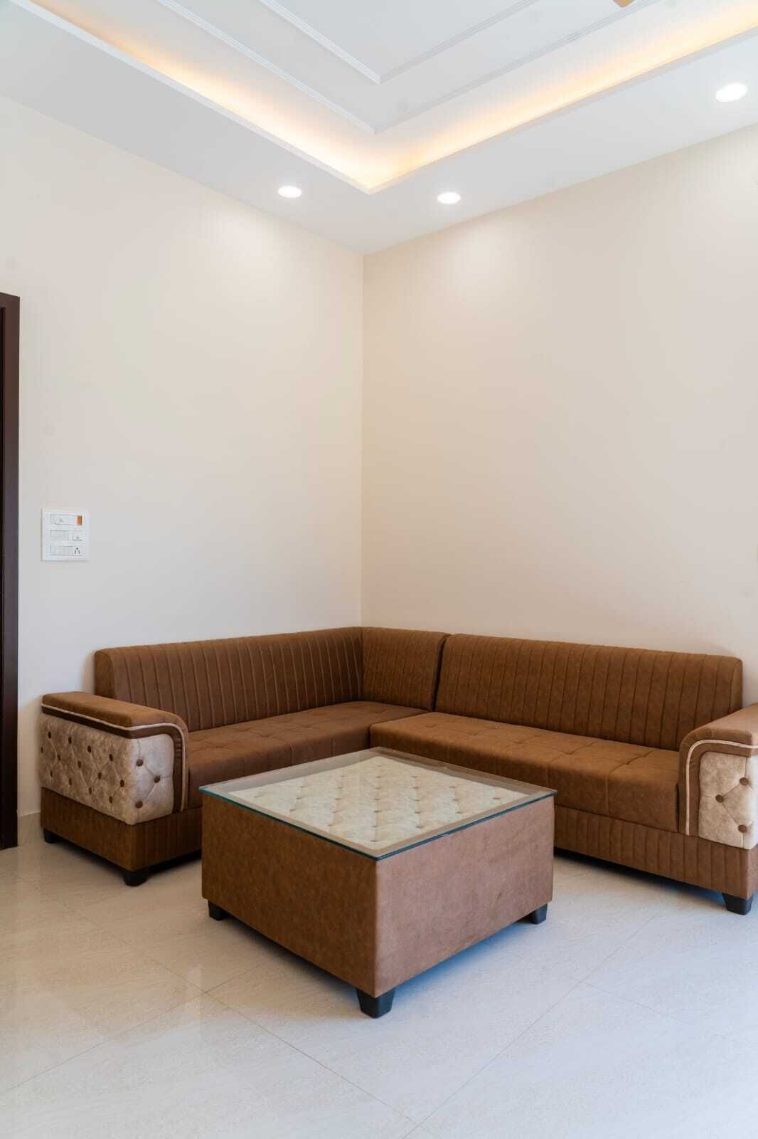 A modern living room with a brown sectional sofa, a glass-top coffee table, and a small side table.