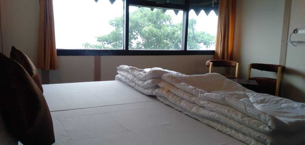 A room with a bed, a window with curtains, and a chair.