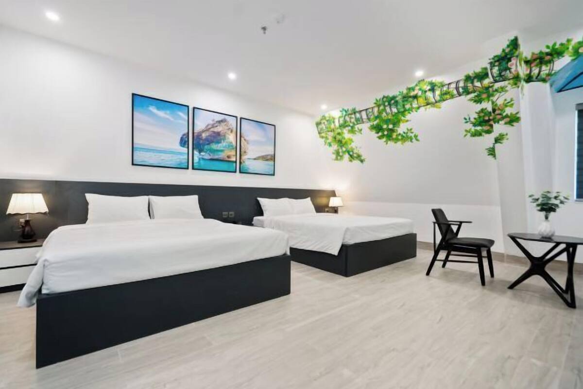 Habitació d'hotel amb dos llits, una cadira, una taula petita i decoració mural.