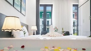 Une chambre d’hôtel avec un lit, une lampe, une fenêtre et une vue sur les immeubles.